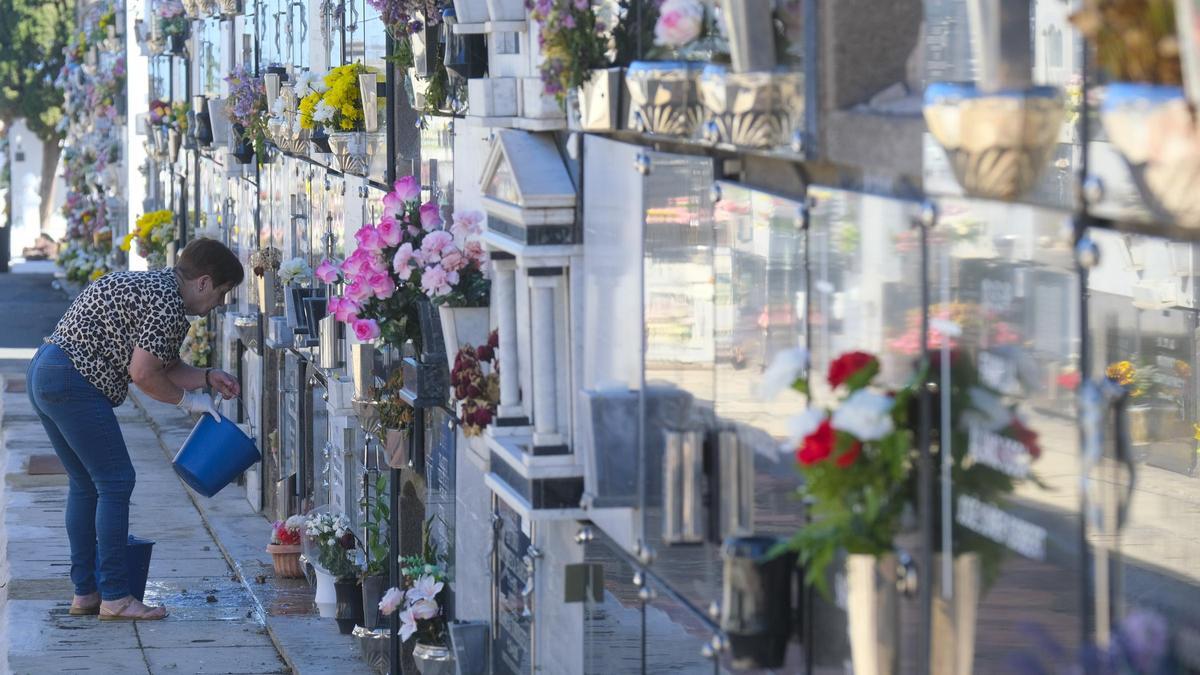 Una mujer limpia la lápida de un nicho en el cementerio de San Lázaro.
