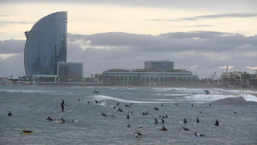 Surferos en la playa de la Barceloneta, en un día lluvioso