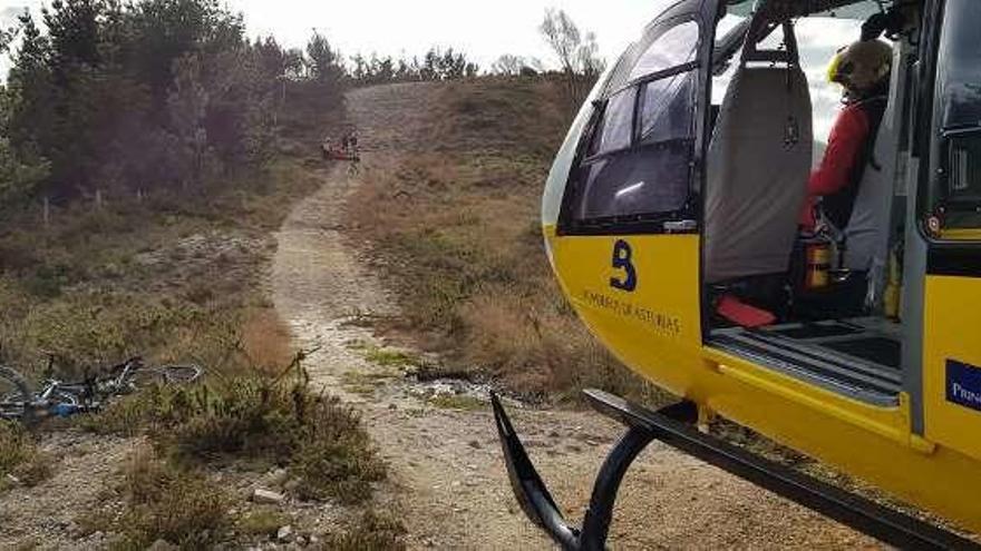 El helicóptero de rescate de los bomberos de Asturias, con el ciclista al fondo.