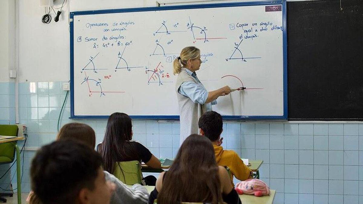 Una profesora imparte una clase a sus alumnos en el aula.