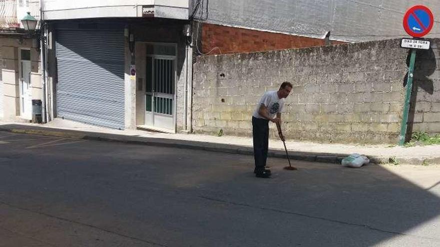 Un vecino barre la tierra de todo el frente de su vivienda. // L.F.