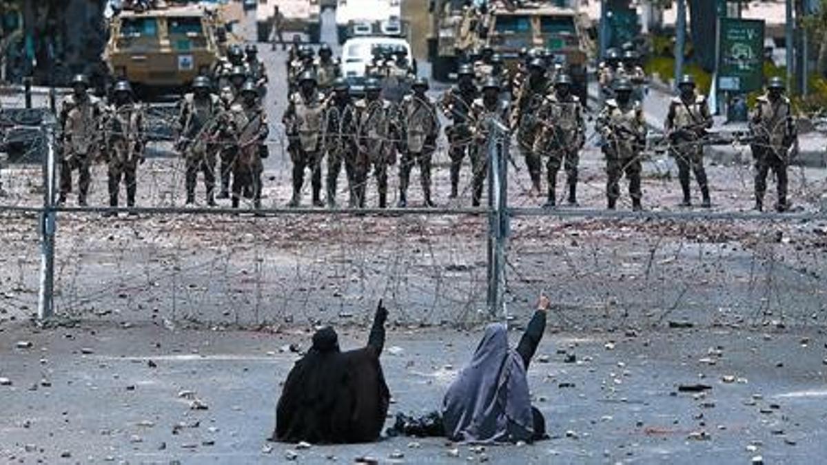 Dos seguidoras de Mursi protestan en el suelo frente a los soldados, el lunes.