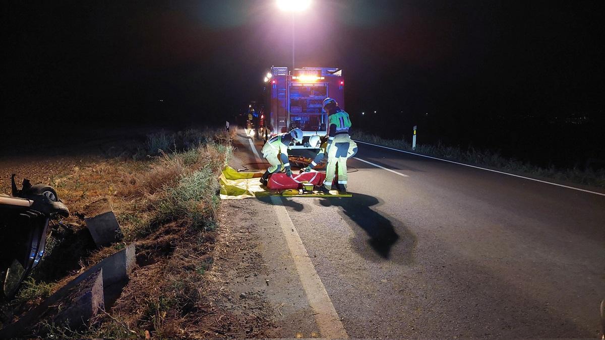 Los equipos de emergencias trabajan en el lugar del accidente en el que ha fallecido una mujer al volcal su coche en la carretera de Guadalcázar.