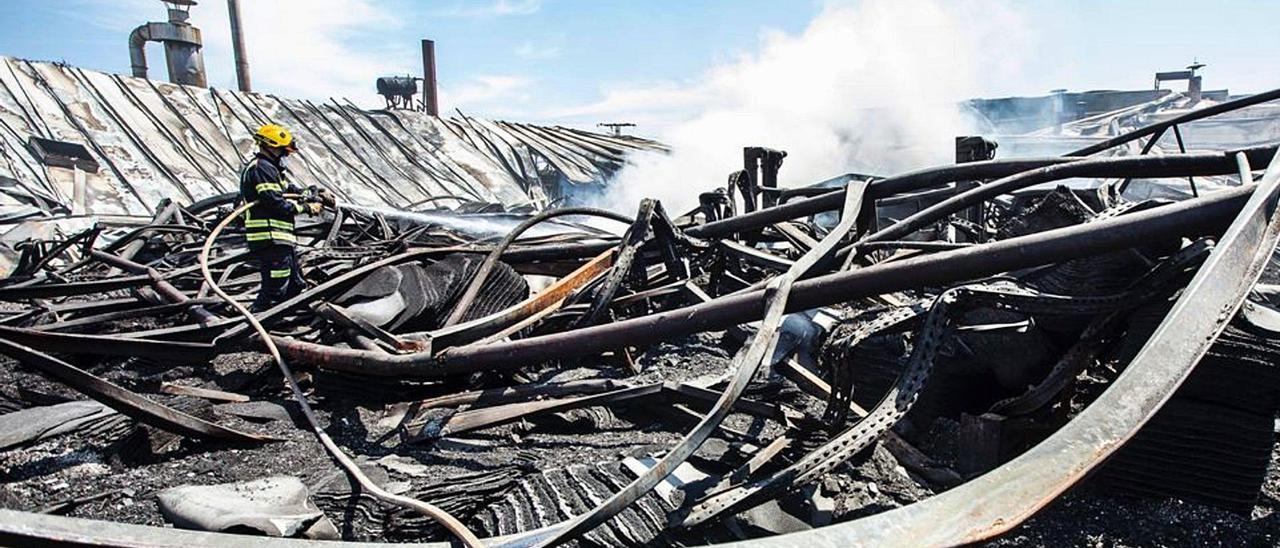 Un bombero sofoca esta semana un rebrote del incendio durante el desescombro de la fábrica calcinada el 11 de julio