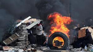 Manifestantes se cubren tras varias barricadas mientras se enfrentan a la policía en el décimo día de de protestas contra el Gobierno de Lenín Moreno. 