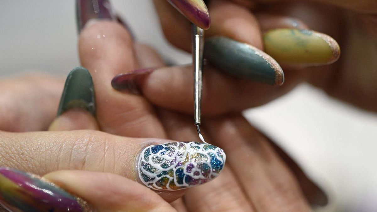Una manicurista realiza una manicura a una clienta.