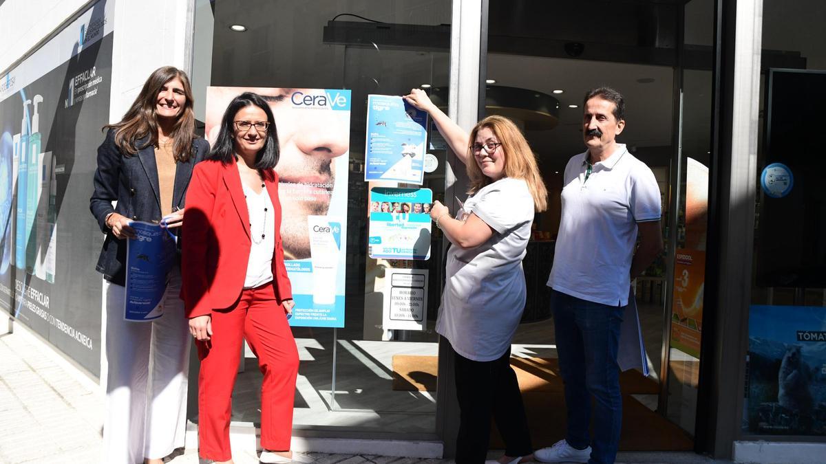 Representantes de Sanidade y del Colegio de Farmacéuticos esta mañana ante uno de los carteles en una farmacia en Moaña