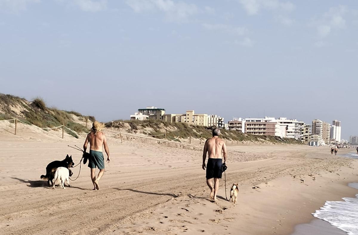 Dos vecinos pasean por la zona de playa en la que limitan los dos términos municipales.