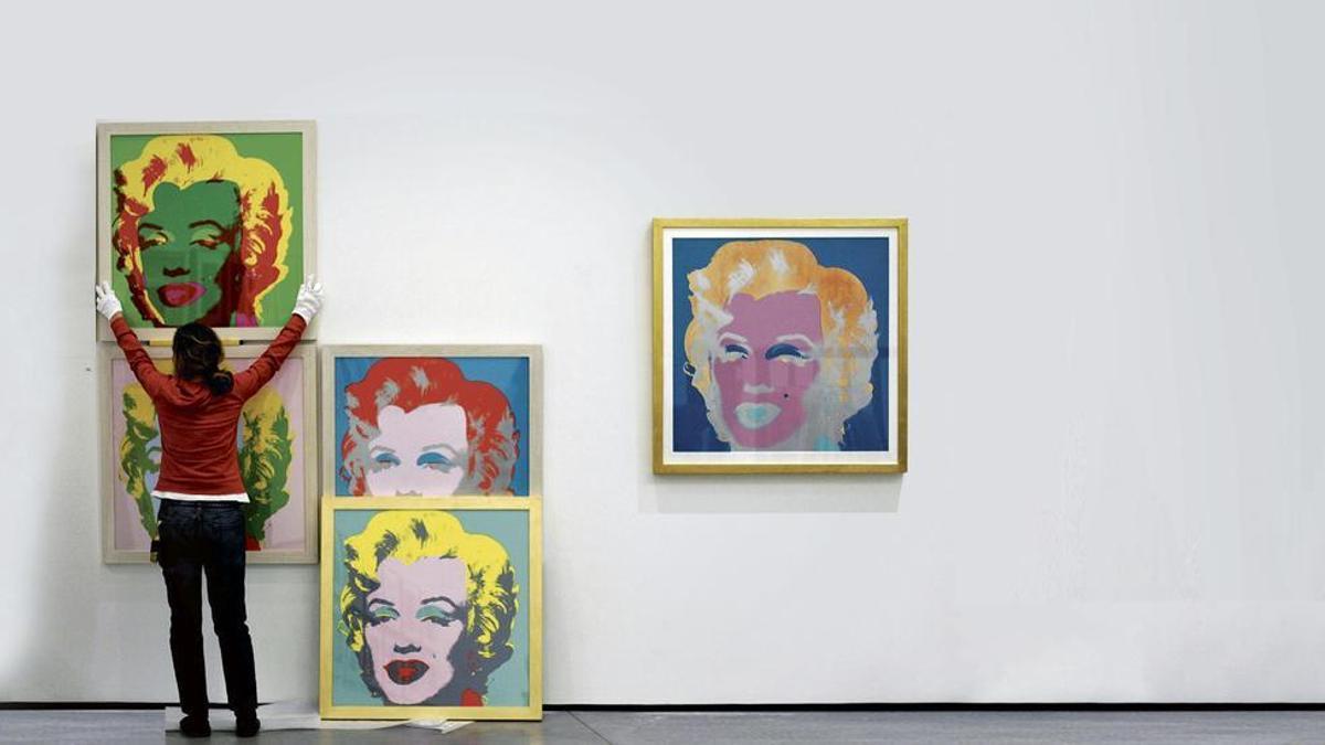 Una operaria traslada retratos de Marilyn Monroe en una exposición de Andy Warhol.