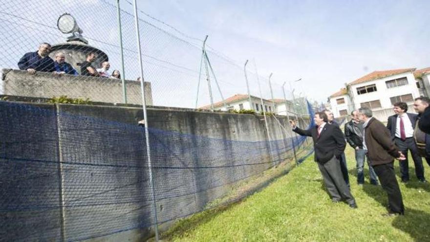 El alcalde, ayer, charla con los exoperarios de la fábrica de armas encerrados en la sede de la factoría y (derecha) una parte de las instalaciones deportivas de la entidad. / 13fotos