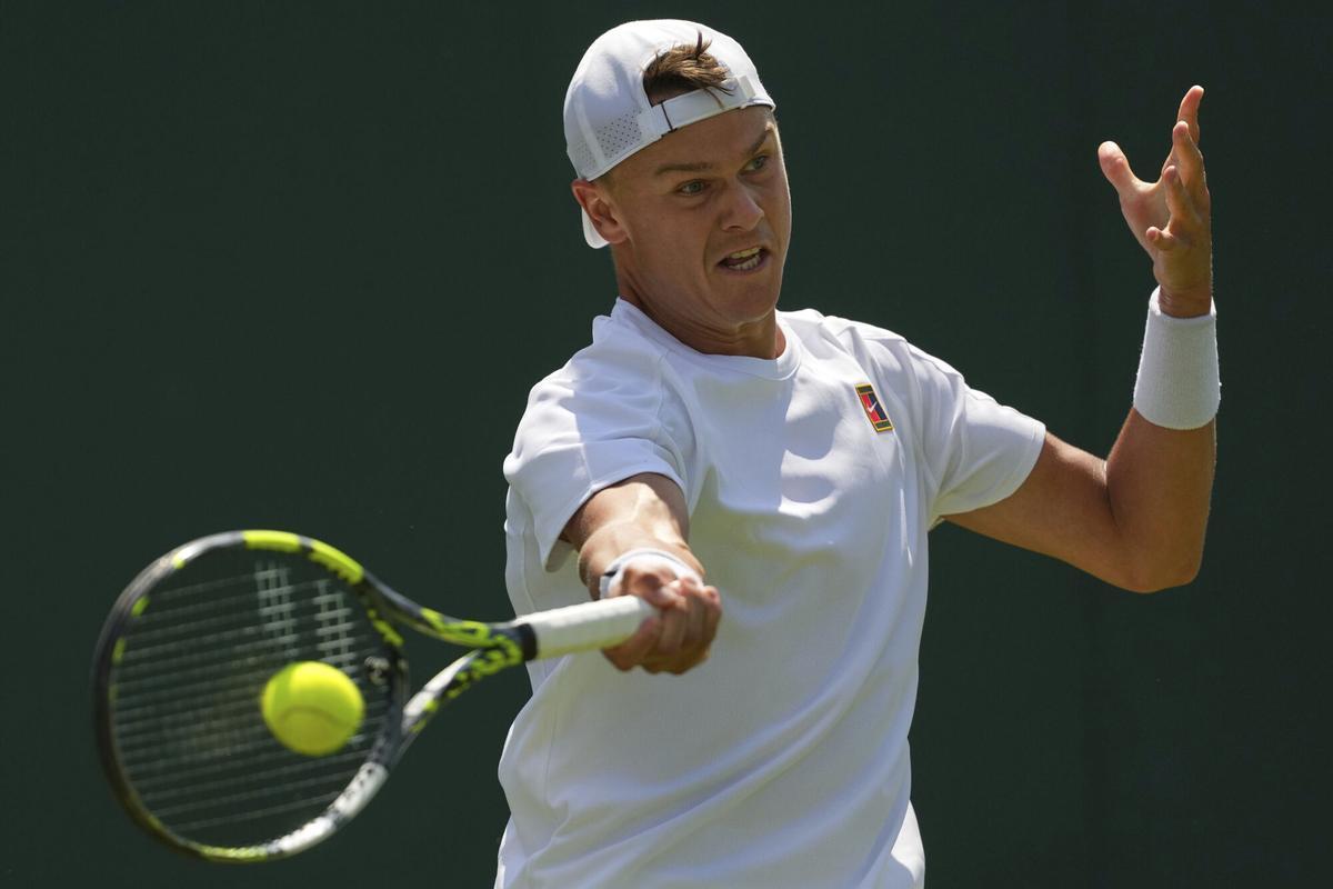 Holger Rune of Denmark returns to Nicolas Jarry of Chile in their first round men's singles match at the Wimbledon Tennis Championships in London, Monday, June 30, 2025. (AP Photo/Joanna Chan)