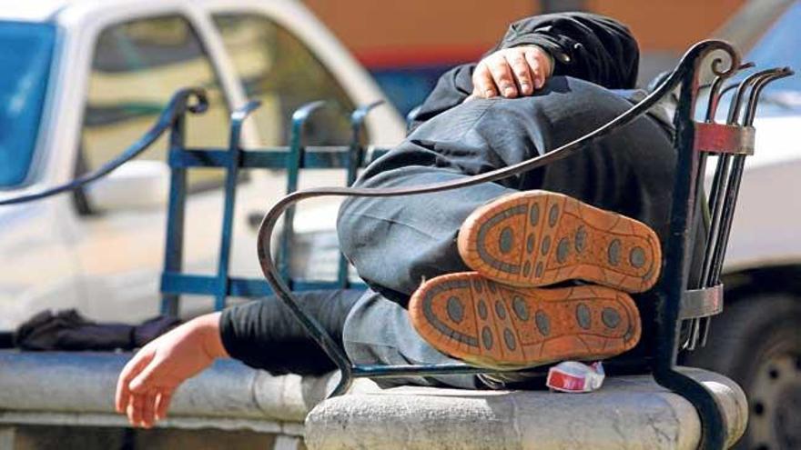 Un ´sin techo´ descansa en un banco de la plaza del Hospital General.