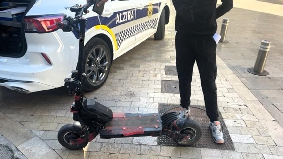 Un patinete rente a un coche de la Policía Local de Alzira.
