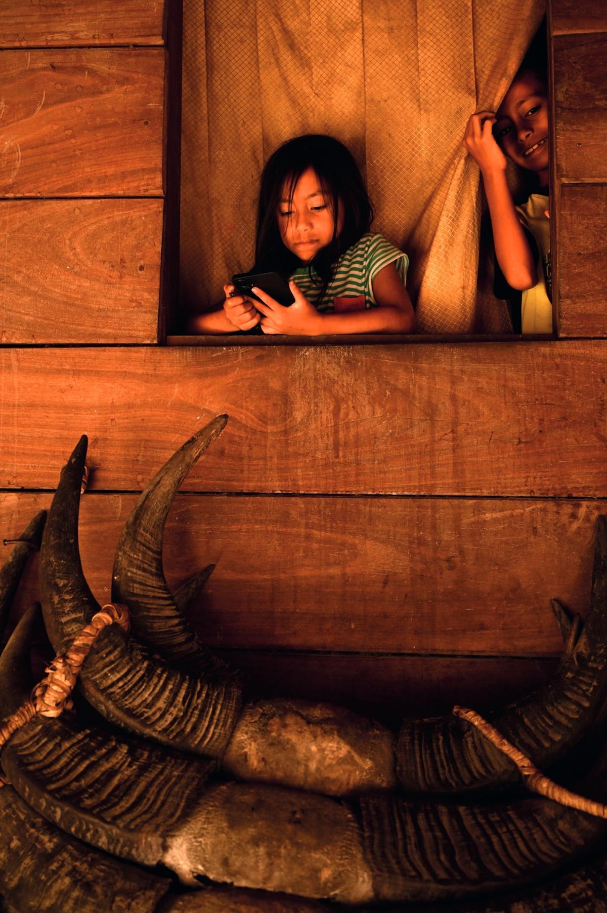 Niños marapu se asoman sobre cuernos de búfalo de agua que decoran su hogar