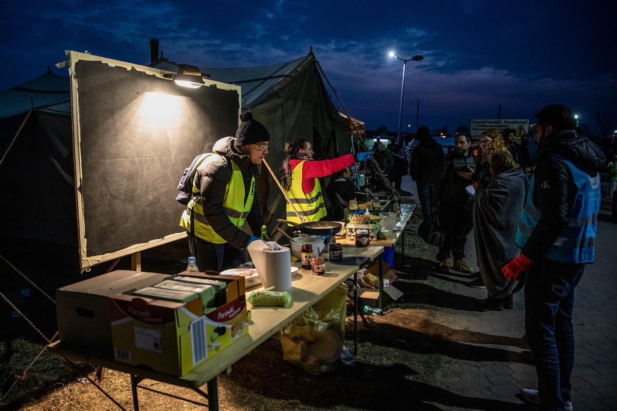 Un grupo de voluntarios sirve comida a refugiados procedentes de Ucrania en el puesto fronterizo de Medyka, en Polonia.