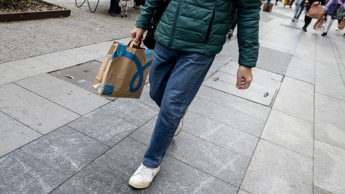 Un hombre camina con una bolsa con compra de un centro comercial durante la campaña del Black Friday.