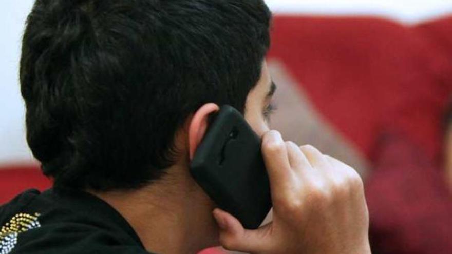 Un adolescente habla por un teléfono móvil.