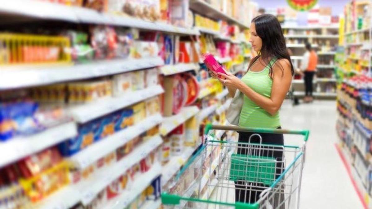 Una mujer mira un producto en un supermercado.