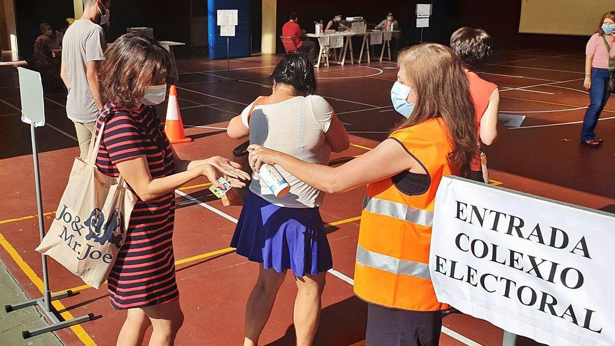 Una voluntaria reparte gel desinfectante a la entrada de un colegio vigués el 12 de julio.