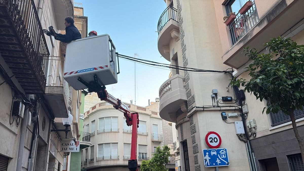Operacios con una plataforma elevadora para retirar el tendido eléctrico en puntos del centro de Elche