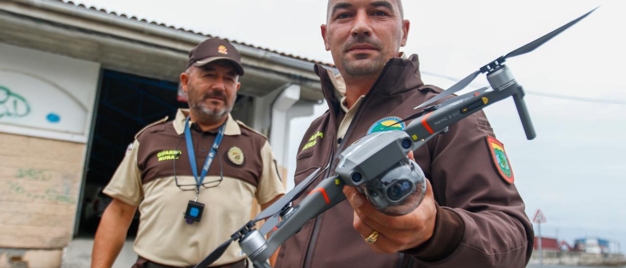 Dos guardas rurales muestan el dron adquirido por la OPP-20, esta mañana junto a la lonja de A Illa