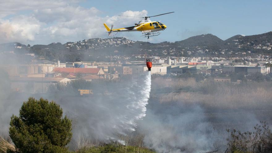 Un helicóptero de Ibanat descarga agua al sobrevolar la zona de ses Feixes.