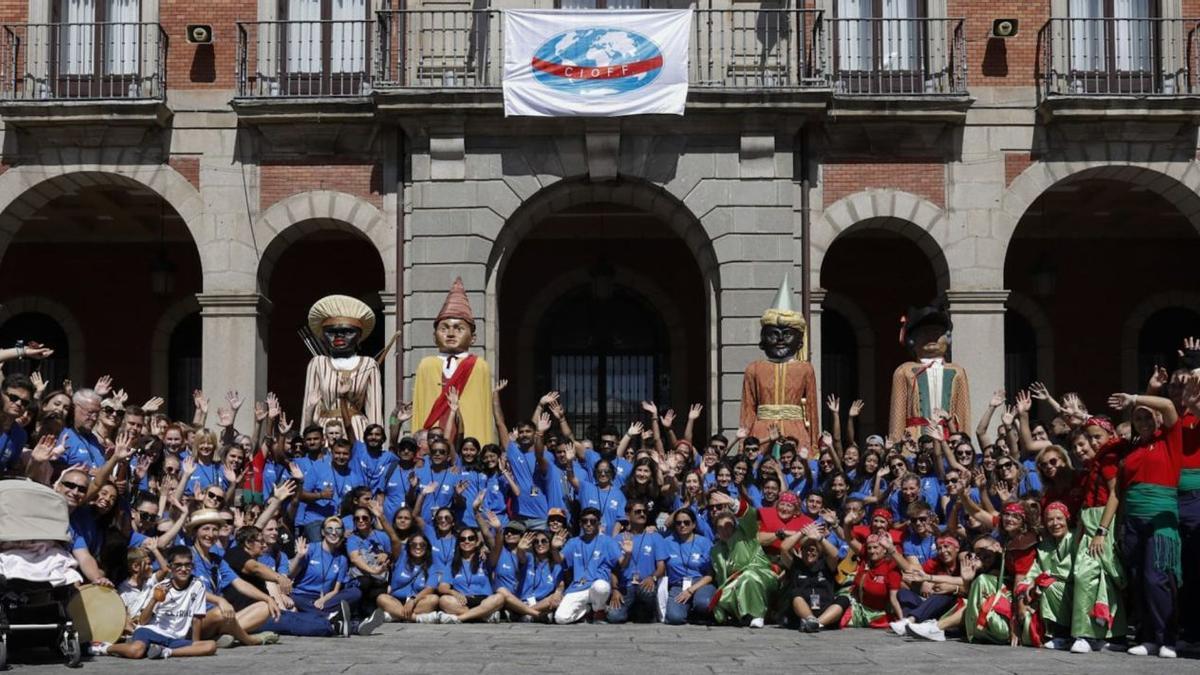 Integrantes de los grupos que participan en el festival con los gigantes de Zamora y los miembros de Tradición y Música Popular con la bandera de CIOFF colgada en el Ayuntamiento. | Ana Burrieza |  A. B.