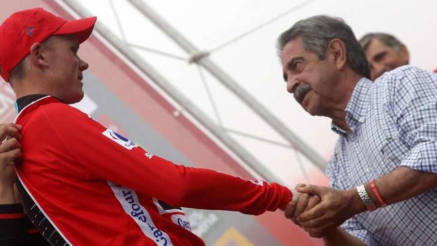 El presidente de Cantabria, Miguel Ángel Revilla, coge la mano del líder, Chris Froome, en el podio de Los Machucos.