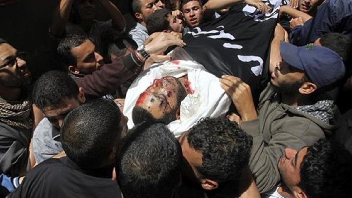 Un grupo de palestinos cargan con el cadáver del joven asesinado durante su funeral en Shati, este martes.