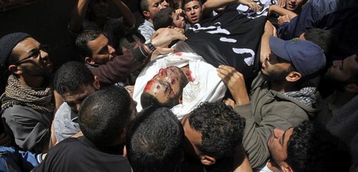 Un grup de palestins carreguen amb el cadàver del noi assassinat durant el seu funeral a Xati, aquest dimarts.