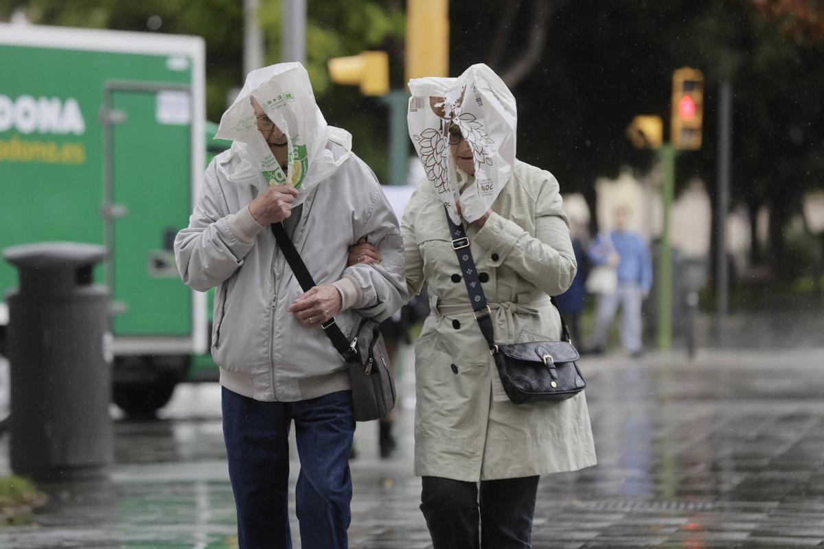 Dos ciudadanos se protegen de la lluvia con bolsas de plástico en la cabeza