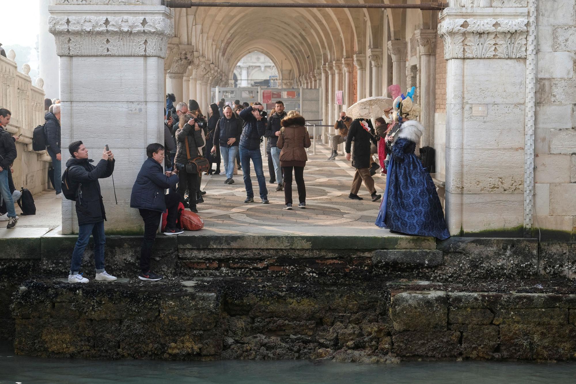 Tourists take pictures during a severe low tide in the lagoon city of Venice