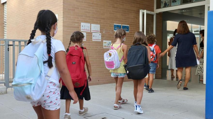 Varios niños entran al centro escolar en el primer día de colegio.