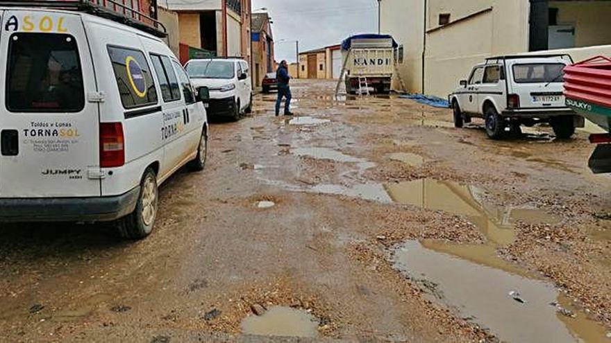 Un vecino sortea los baches repletos de agua formados en la travesía de San Antón de Toro por la cesión del terreno.