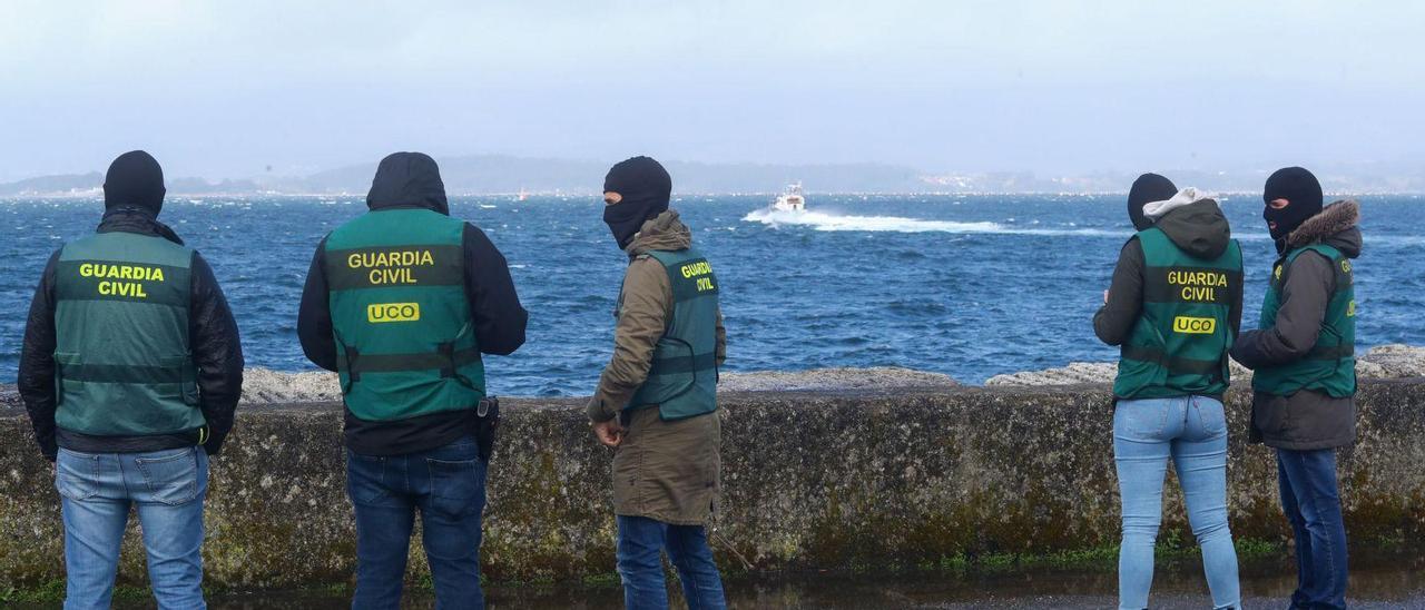 Agentes de la UCO de la Guardia Civil contemplan desde Vilaxoán la zona en la que apareció el narcosubmarino.