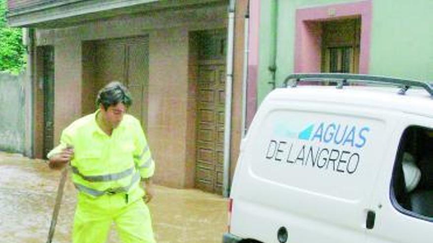 Un operario de Aguas de Langreo trabaja en una calle inundada de Ciaño.