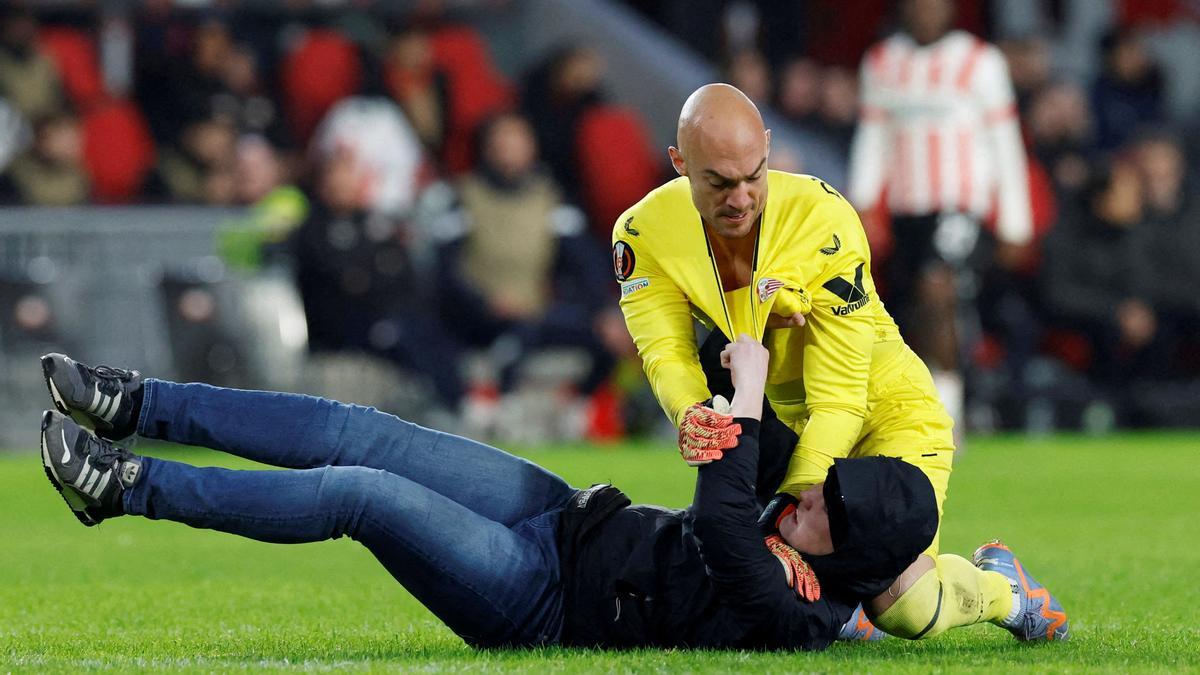 Un espectador salta al campo durante el PSV-Sevilla e intenta agredir a Dmitrovic.