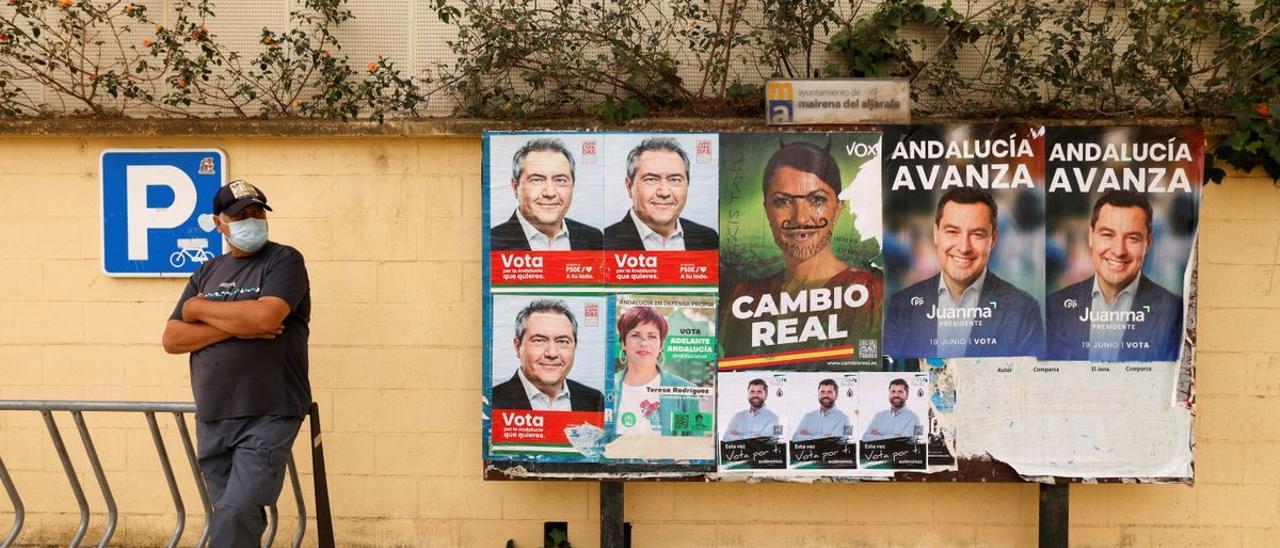 Un hombre frente a unos carteles electorales de las elecciones en Andalucía, en Mairena de Aljarafe, Sevilla.