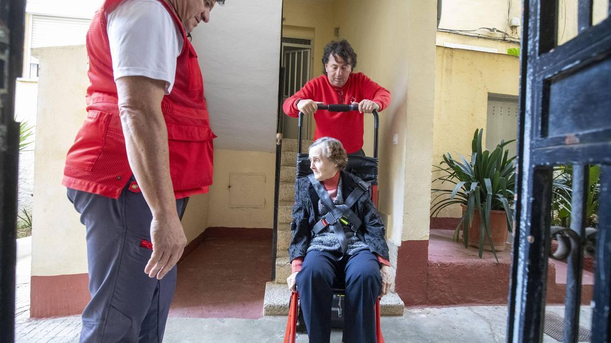 Elisa García baja de su casa en Palma con voluntarios de la Cruz Roja.