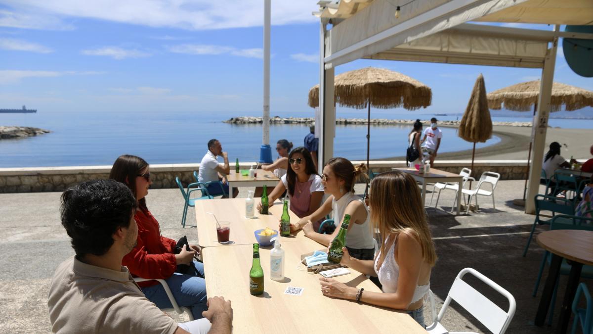Varias personas disfrutan de la terraza en el paseo marítimo de Pedregalejo, uno de los barrios que forman parte del plan para descentralizar el turismo en Málaga.