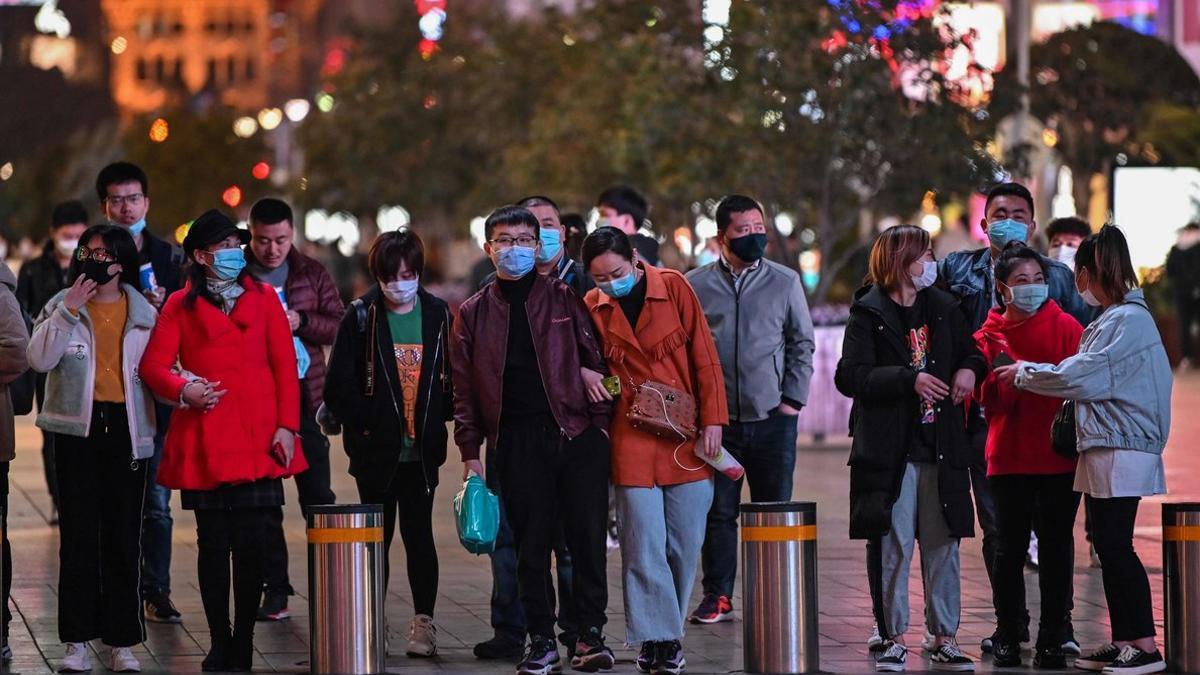 Un grupo de personas con máscaras, en el distrito comecial de Shanghái.
