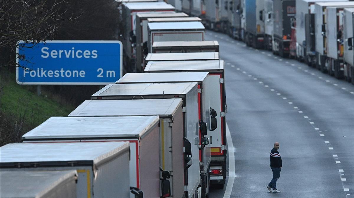 A driver stands in the road as freight lorries and goods vehicles queue on a closed section of the M20 motorway which leads to the Port of Dover  near Ashford in Kent  south east England on December 22  2020  after a string of countries banned travel including accompanied freight arriving from the UK  due to the rapid spread of a new strain of coronavirus  - Britain s critical south coast port at Dover said on December 20 it was closing to all accompanied freight and passengers due to the French border restrictions  until further notice   (Photo by JUSTIN TALLIS   AFP)