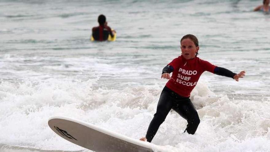 Una niña practica con su tabla de surf sobre las olas de la playa de A Lanzada.  //Muñiz