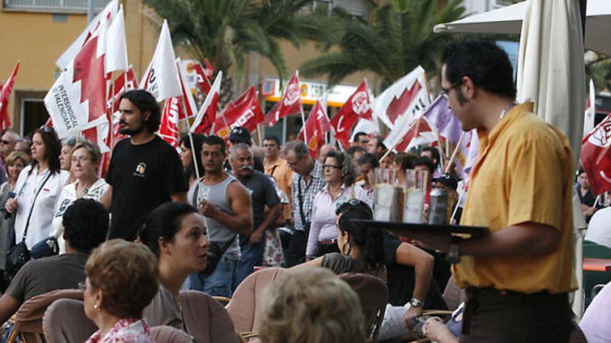 Un camarero sirve a los clientes mientras los manifestantes protestan contra la reforma laboral en Alicante