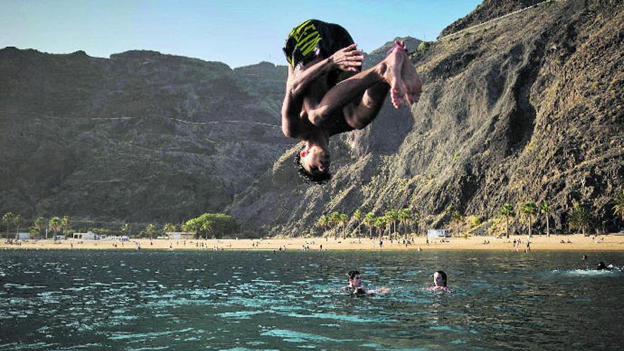 Un joven se tira al agua de forma acrobática ayer en la playa de Las Teresitas.