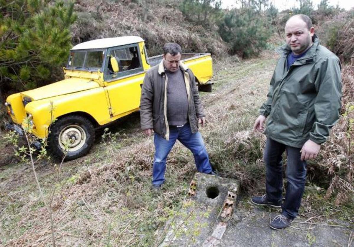 Los comuneros Miguel Meneses y Alfredo Iglesias, ayer, en el pozo  "O buraco dos mouros", en Pinzás.  // J. Lores