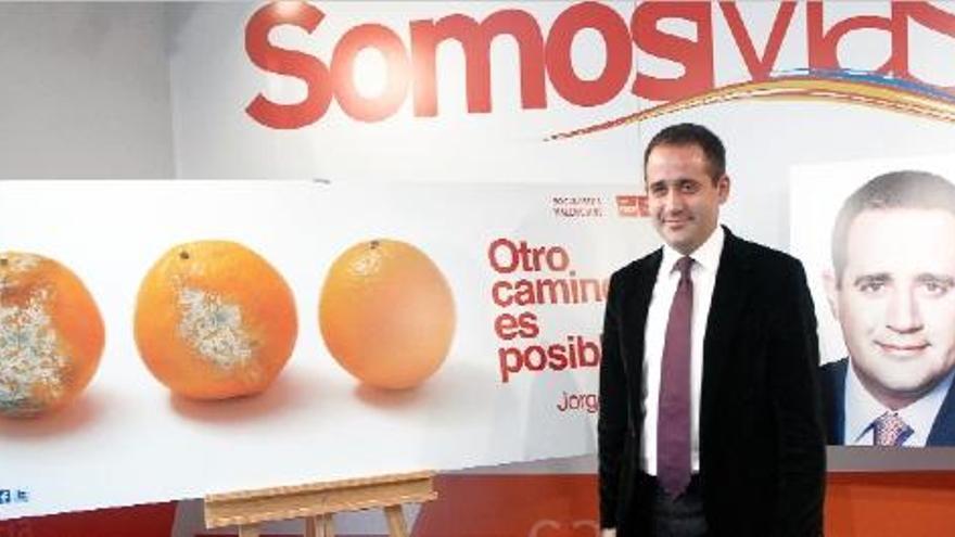 El candidato socialista Jorge Alarte posa ante el cartel de &quot;Otro camino es posible&quot;, con tres naranjas.