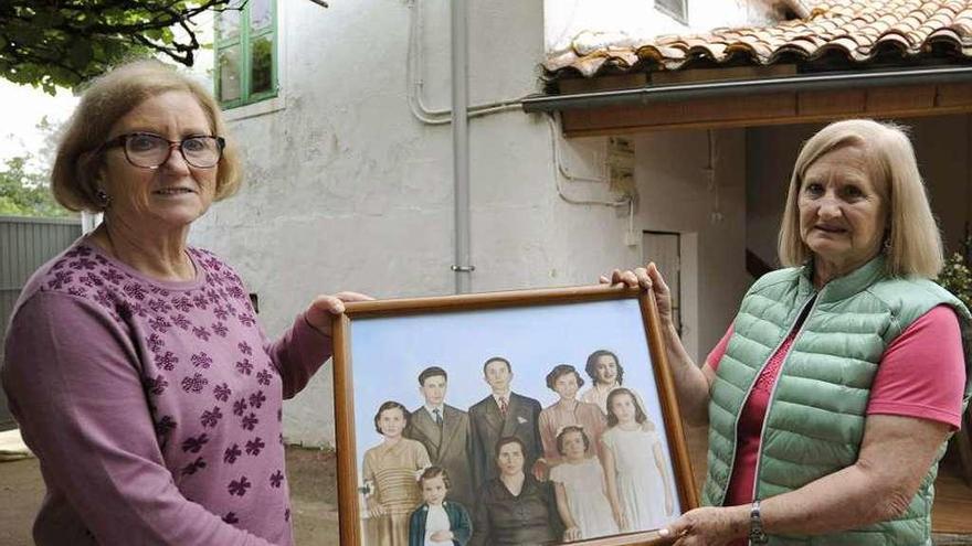 Sara y Dolores portan una foto de los padres y los siete hermanos en la casa familiar. // Bernabé/Javier Lalín