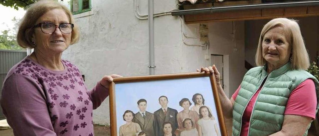 Sara y Dolores portan una foto de los padres y los siete hermanos en la casa familiar. // Bernabé/Javier Lalín