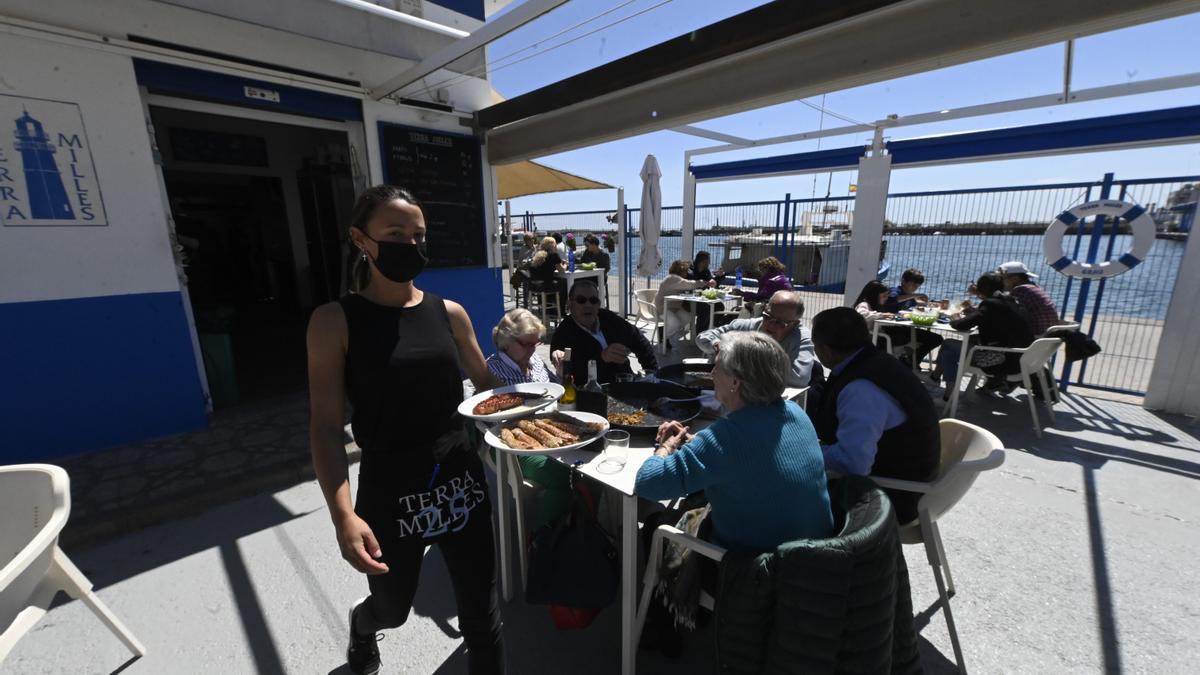 Una camarera sirve unos platos en un restaurante del Grau de Castelló.